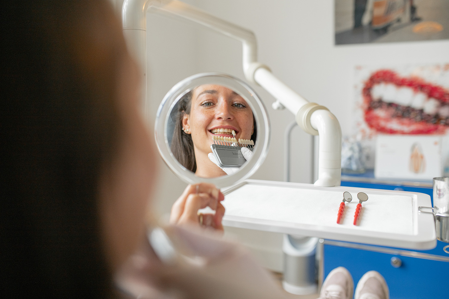 Patientin begutachtet die Zahnfarbe im Spiegel vor der Veneers-Behandlung.