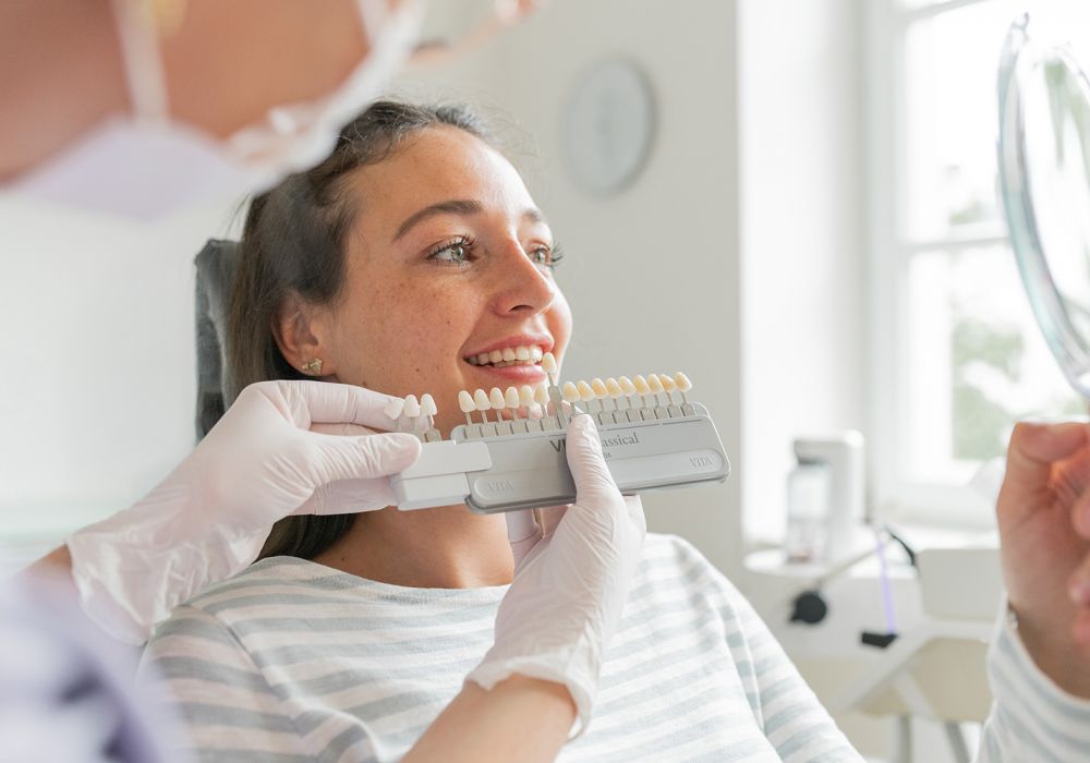Patientin vergleicht Zahnfarben für die Auswahl ihrer Veneers.